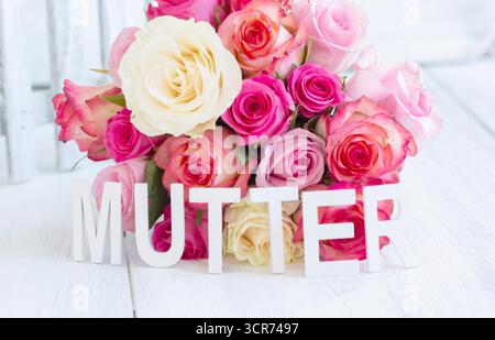 rosa (specifica Rosa), lettere colorate MUTTER davanti a un mazzo di rose, immagine simbolica della festa della mamma Foto Stock