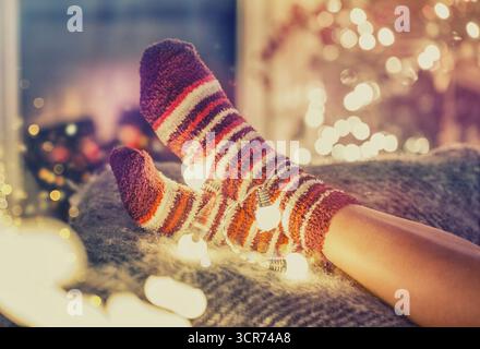 piedi in calze a righe e luci fatate sul divano Foto Stock