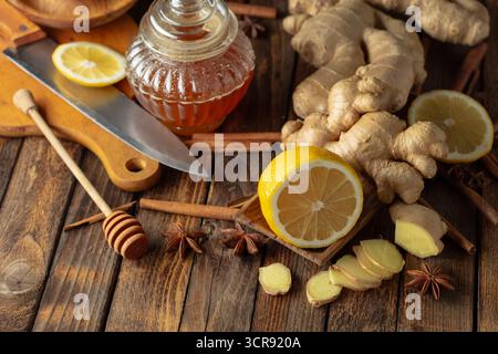 Ingredienti per preparare il tè allo zenzero. Zenzero, limone, miele, anice e bastoncini di cannella su un vecchio tavolo da cucina. Foto Stock