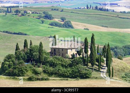Un antico casale circondato da cipressi su una verde collina in Toscana, a sud di Pienza, Toscana, Italia Foto Stock