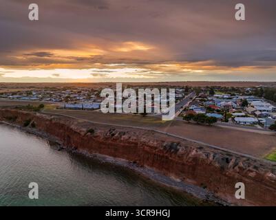 Vista aerea di un tramonto nebbioso su una città costiera in alto sulle scogliere di Ardrossan, sulla penisola di Yorke, nell'Australia meridionale. Foto Stock