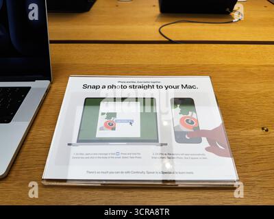 Manchester, Regno Unito - 29 settembre 2025: Un cartello dimostrativo su una scrivania di legno mostra come scattare una foto direttamente su un Mac. Ambiente tecnologico pulito e moderno per e. Foto Stock