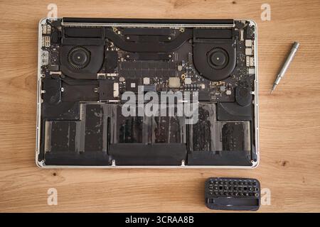 Computer portatile smontato insieme a vari utensili posizionati ordinatamente su una superficie in legno per le riparazioni Foto Stock