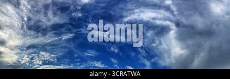 Un ampio panorama che mostra cieli blu vibranti pieni di nuvole e spettacolari. Foto Stock