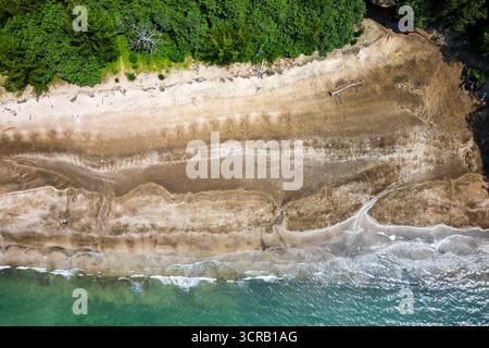 Vista dall'alto verso il basso della foresta pluviale tropicale che incontra il mare turchese su una spiaggia selvaggia del Borneo Foto Stock