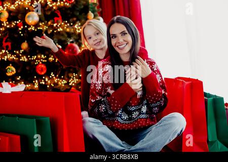 Madre e figlia trascorrono un Natale gioioso in un accogliente soggiorno con decorazioni, festeggiando e godendo dei regali Foto Stock