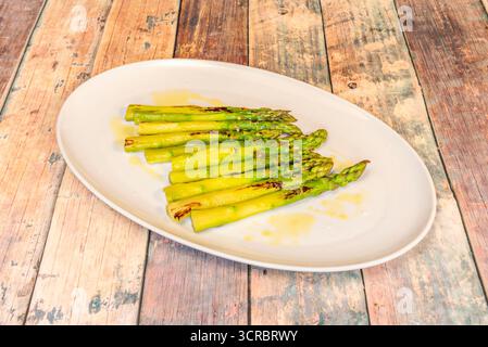 Una selezione di verdure alla griglia, con asparagi selvatici come pezzo forte, mais dolce e peperoni piquillo su una base di crema all'aglio arrosto Foto Stock