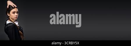 Una ragazza con trecce indossa un abito gotico per festeggiare Halloween con stile Foto Stock