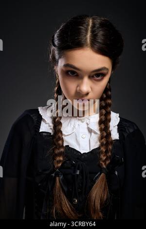Una ragazza con trecce indossa un abito gotico che ricorda il mercoledì. Foto Stock