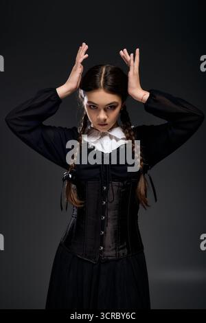 Una ragazza con trecce indossa un abito gotico che ricorda un personaggio spaventoso per Halloween. Foto Stock
