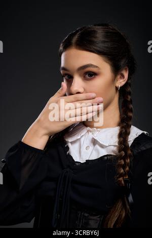 Una ragazza con trecce indossa un abito gotico, che incarna un personaggio del mercoledì per Halloween. Foto Stock