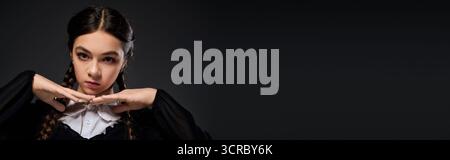 Una ragazza vestita in stile gotico mercoledì posa drammaticamente per Halloween, striscione Foto Stock