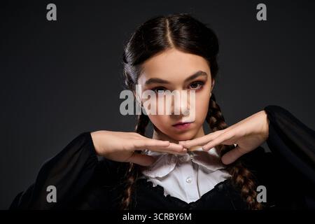 Una ragazza con trecce indossa un abito mercoledì in stile gotico, che incarna un personaggio spaventoso per Halloween. Foto Stock