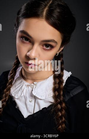 Una ragazza con trecce vestita in stile gotico incanta il personaggio del mercoledì per Halloween. Foto Stock
