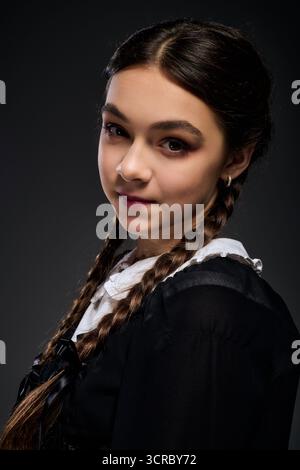 Una ragazza in treccia indossa un abito gotico del mercoledì, che incarna perfettamente lo spirito di Halloween. Foto Stock