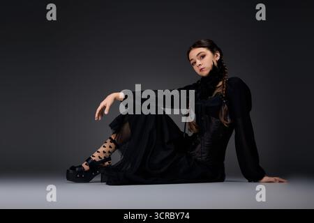 Una ragazza con trecce indossa un abito gotico ispirato a un personaggio spaventoso del mercoledì Foto Stock