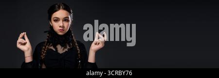 Una ragazza vestita con un costume gotico incarna un personaggio del mercoledì per le festività di Halloween, lo striscione Foto Stock