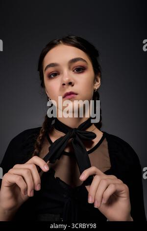 Una ragazza vestita da spaventoso personaggio del mercoledì cattura l'essenza di Halloween con le sue trecce. Foto Stock