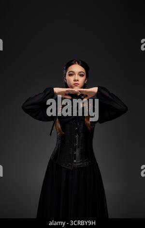 Una ragazza con trecce indossa un abito in stile gotico ispirato al mercoledì di Halloween. Foto Stock