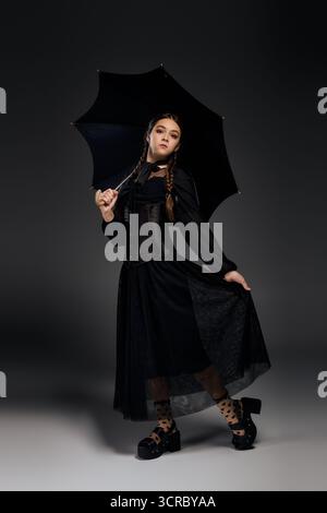 Una ragazza con trecce indossa elegantemente un abito gotico, catturando in modo splendido lo spirito di Halloween. Foto Stock