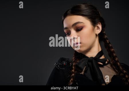 Una ragazza con trecce indossa un abito in stile gotico, abbracciando lo spirito spettrale di Halloween. Foto Stock