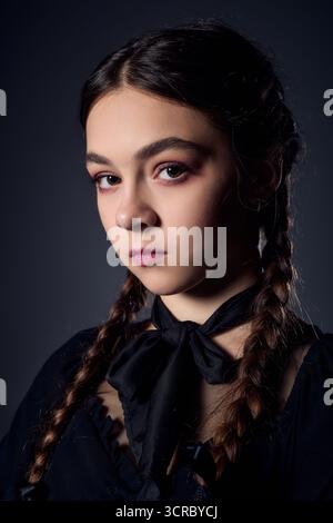 Una ragazza con trecce indossa un abito gotico ispirato a un popolare personaggio di Halloween. Foto Stock