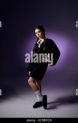 Una ragazza in treccia indossa un abito gotico del mercoledì che cattura lo spirito di Halloween. Foto Stock