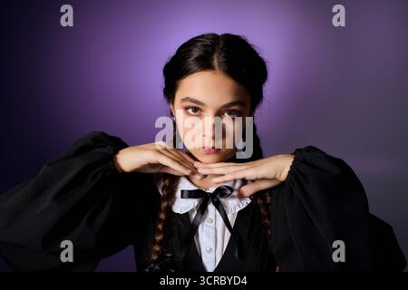 Una ragazza con trecce indossa un abito gotico che incarna un personaggio del mercoledì durante le festività autunnali. Foto Stock
