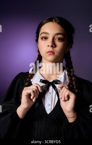 Una ragazza con trecce indossa un abito in stile gotico del mercoledì, che abbraccia lo spirito di Halloween. Foto Stock
