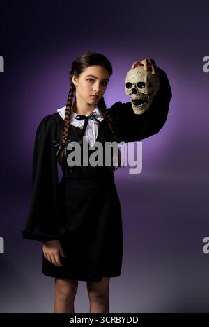 Una ragazza con trecce indossa un abito in stile gotico, con il teschio, che abbraccia la stagione spettrale. Foto Stock