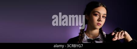 La ragazza con trecce indossa un abito gotico ispirato a un personaggio del mercoledì per Halloween, striscione Foto Stock