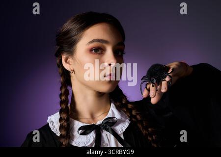 Vestita da spaventoso personaggio del mercoledì, una ragazza con trecce mostra il suo lato giocoso per Halloween. Foto Stock