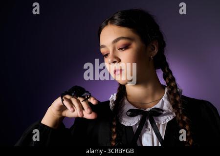 Una ragazza con trecce ama Halloween, vestita in stile gotico come un famoso personaggio del mercoledì. Foto Stock