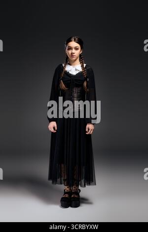 Una ragazza con trecce indossa un abito gotico ispirato al personaggio del mercoledì durante il periodo di Halloween. Foto Stock