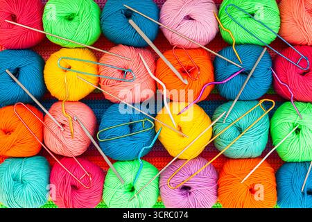 Tutto per maglieria a mano. Tessuto lavorato a maglia multicolore realizzato a mano con sfere di fili multicolori, spille e vari aghi per maglieria. Foto Stock