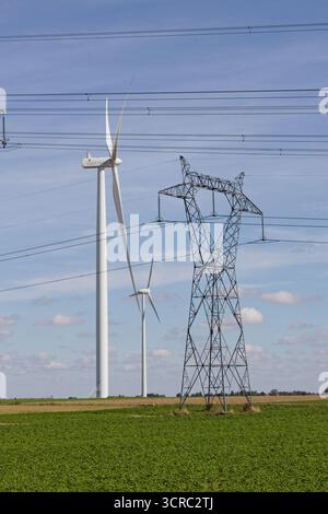 Turbine eoliche e piloni elettrici. Generazione di energia elettrica e trasporto di elettroni tramite fili. Erogare energia generata alle sottostazioni. Foto Stock