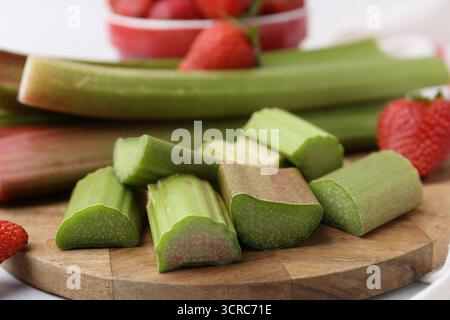 Tagliare il rabarbaro fresco e le fragole sul tavolo, primo piano Foto Stock