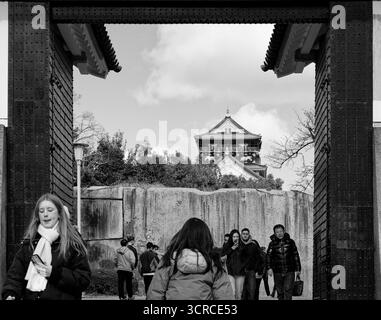 I visitatori camminano attraverso la grande porta del Castello di Osaka, con la torre principale incorniciata contro il cielo nuvoloso Foto Stock
