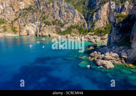 Incredibile volo aereo in droni sopra le acque cristalline turchesi e le maestose scogliere di Paleokastritsa, Corfù. Le piccole barche attraccano nell'appartata ba Foto Stock
