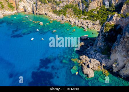 Vista aerea mozzafiato delle barche nel turchese Mar Ionio lungo le scogliere rocciose di Paleokastritsa, Corfù, Grecia. Un fantastico viaggio estivo Foto Stock