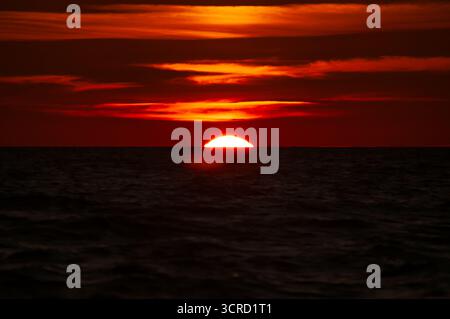Il sole che tramonta con nuvole di colore rosso sulla riva del Mare di Botnia a pori, Finlandia Foto Stock
