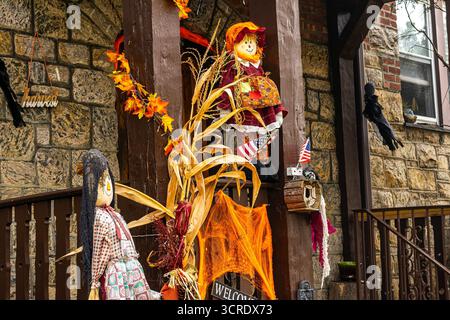 Decorazioni di Halloween su un portico nella campagna del New England, decorazioni per scherzi o dolcetti, decorazioni per il raccolto autunnale con spaventapasseri e gambi di mais Foto Stock