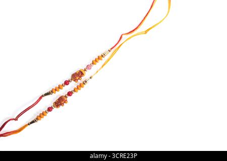 Immagine ravvicinata di due corde decorative con perle di legno e fili rossi e gialli, isolate su uno sfondo bianco pulito. Foto Stock