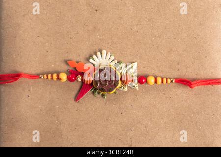 Un colorato braccialetto Rakhi, perfetto per le celebrazioni e i regali di Raksha Bandhan, caratterizzato da un pezzo centrale simbolo Om, perline arancioni e rosse e un re Foto Stock