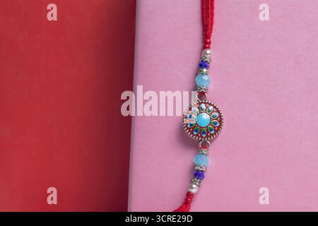 Vivace gioiello fatto a mano bracciale con perline blu e rosse con sfondo rosa per Raksha Bandhan. Foto Stock