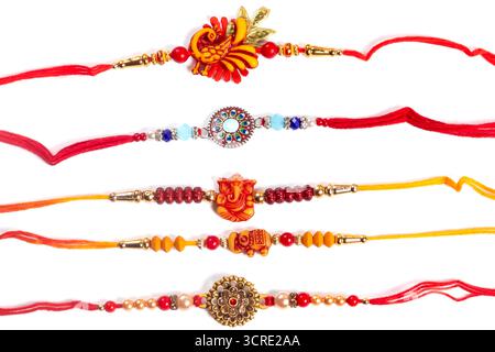 Vibranti bracciali Rakhi con perline, ciondoli e fili luminosi in rosso, arancione e oro. Perfetti per feste indiane e regali di famiglia, questi decori Foto Stock