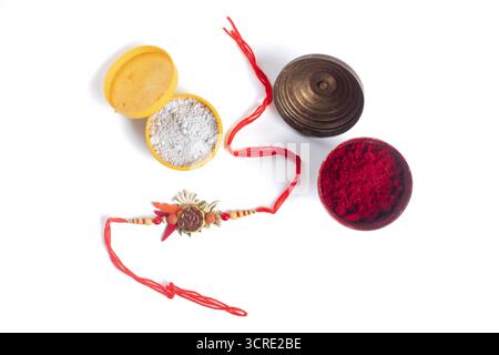 Un colorato set per cerimonie Rakhi con due scatole polvere con polveri bianche e rosse, un Rakhi decorativo con filo rosso e un ciondolo con perline. Perfetto per Foto Stock