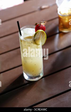 Una vista di un cocktail di colore giallo in un bicchiere a sfera alta. Foto Stock