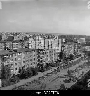 Un'ampia fotografia panoramica ad alto angolo degli anni '1980, che mostra il vasto microdistretto residenziale Artema a Sloviansk, RSS Ucraina. L'immagine cattura l'immensa scala della pianificazione urbana sovietica, con infinite file di blocchi di appartamenti standardizzati prefabbricati (panelka) che si estendono all'orizzonte. Sotto, i cortili tra gli edifici presentano parchi giochi e vegetazione sparsa. Questa visione d'archivio in bianco e nero è un esempio per antonomasia dell'architettura abitativa di massa monotona ma funzionale del tardo periodo sovietico Foto Stock