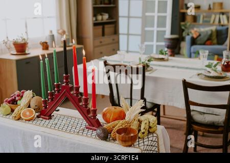 Portacandele Kwanzaa Kinara con candele accese e frutta festiva Foto Stock